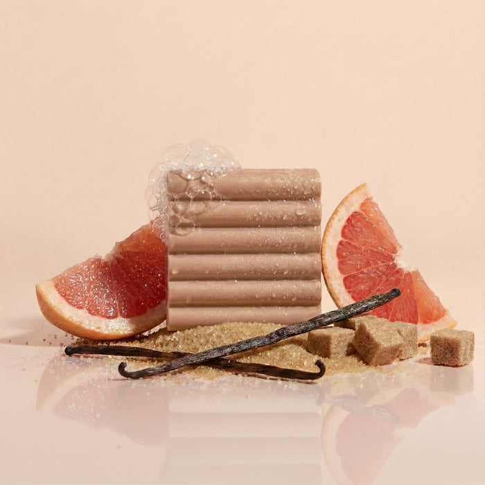 Kitsch Warm Sugar Body Wash Bar with grapefruit slices, vanilla beans, and brown sugar representing the main scent tones on a beige background