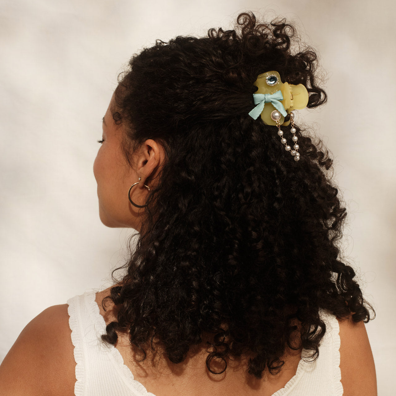 Model with thick curly hair wearing butter yellow KitschPop Cloud Clip with Coastal Cottage Charm Collection – mint bow and pearl chain charms