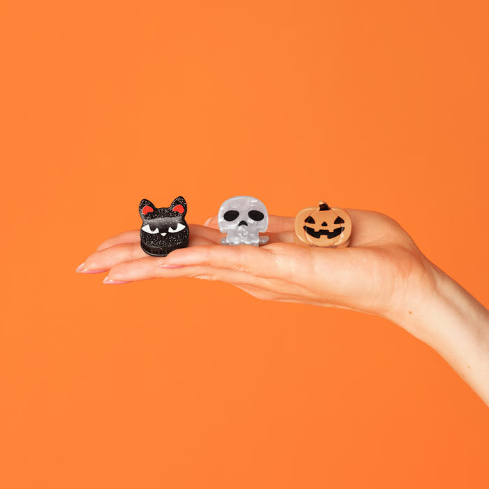 Hand holding the Halloween Mini Claw Clips 6pc Set featuring black cat, skull, and pumpkin mini claw clips.