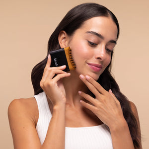 Model using the black Kitsch Lymphatic Contour Face Brush to massage her cheek