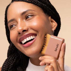 KITSCH Performance Ritual Kit — model using the Terracotta Lymphatic Contour Face Brush to massage her cheek post-workout — helps de-puff a tired-looking face