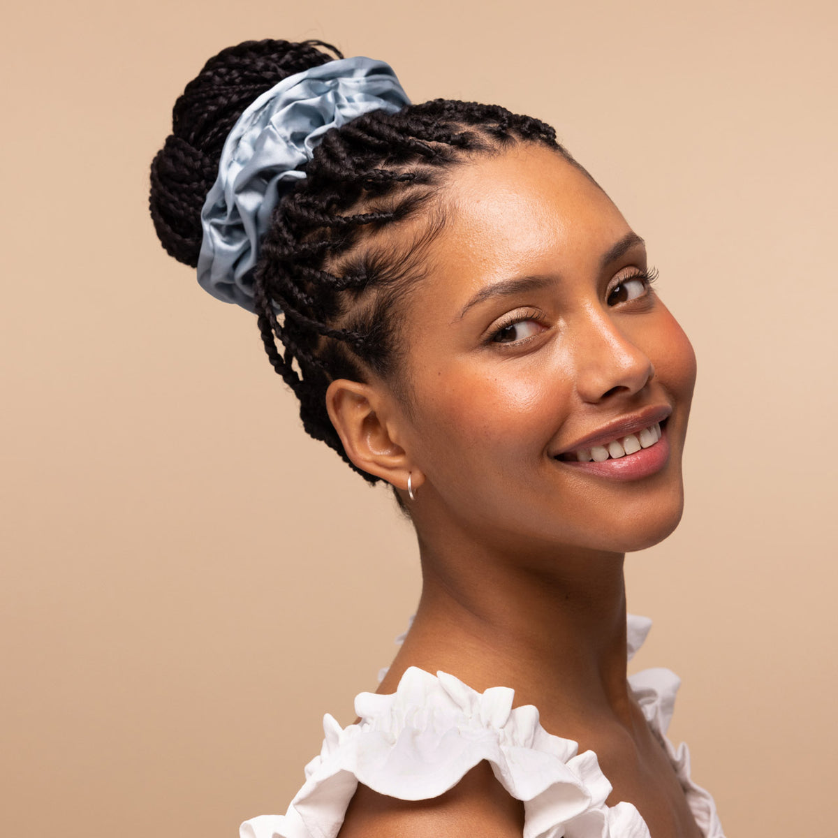 KITSCH Haze Blue Satin Sleep Scrunchies 5pc Set — smiling model with braids in a high bun secured by a haze blue satin scrunchie